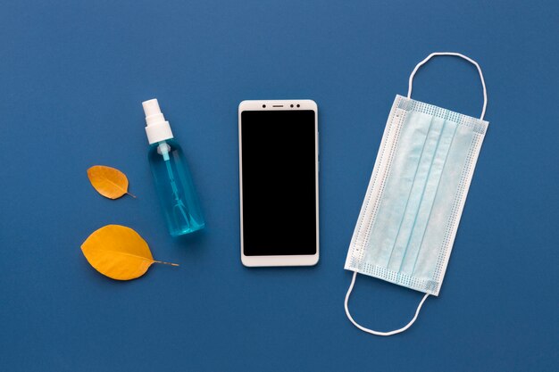 Flache medizinische Maske mit Smartphone und Händedesinfektionsmittel