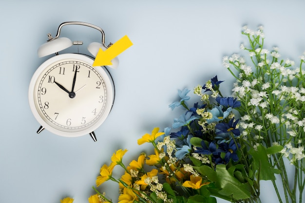 Flache Uhr neben Blumenstrauß