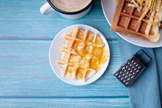 Flache Waffelauflage mit geriebenem Käse und Getränk