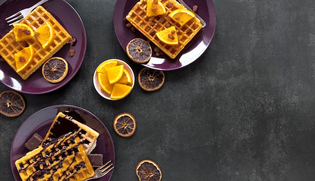 Flache Waffellage auf Tellern mit Schokolade und Zitrusfrüchten