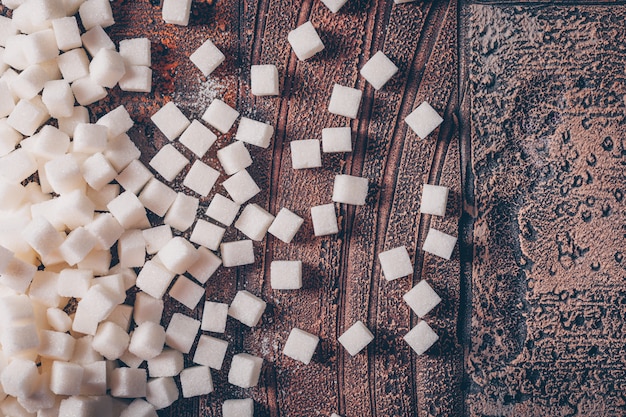 Flache weiße Zuckerwürfel auf dunklen Holztisch legen. horizontal
