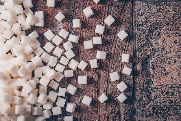 Kostenloses Foto flache weiße zuckerwürfel auf dunklen holztisch legen. horizontal