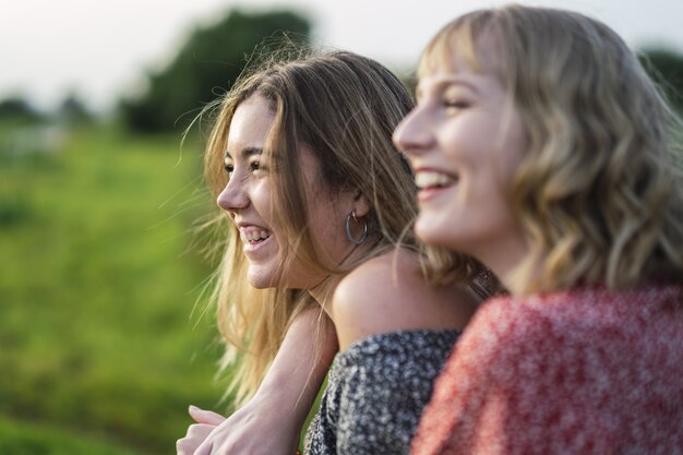 Flacher Fokus von zwei jungen fröhlichen Frauen, die sich in einem Park in Spanien umarmen