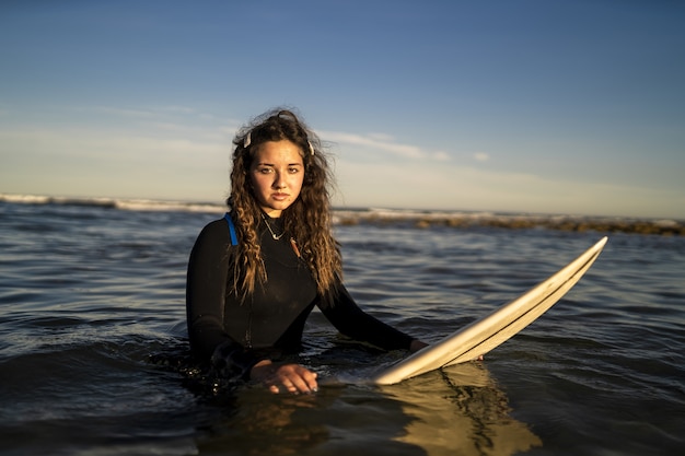 Flacher Fokusschuss einer attraktiven Frau, die am Meer aufwirft, während sie ein Surfbrett hält