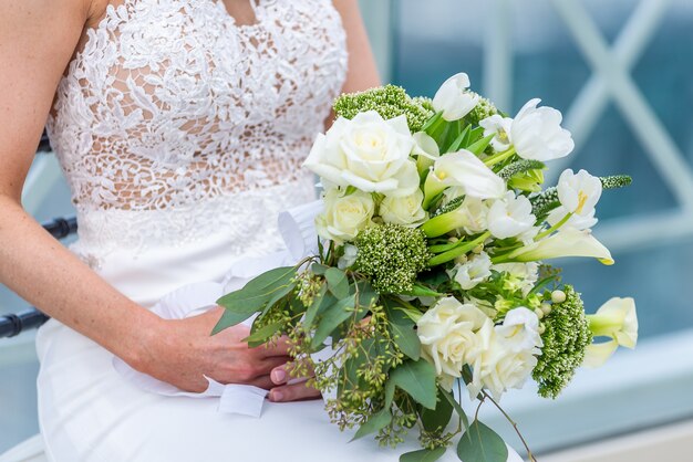 Flacher Fokusschuss einer Braut in einem Hochzeitskleid, das einen Blumenstrauß hält