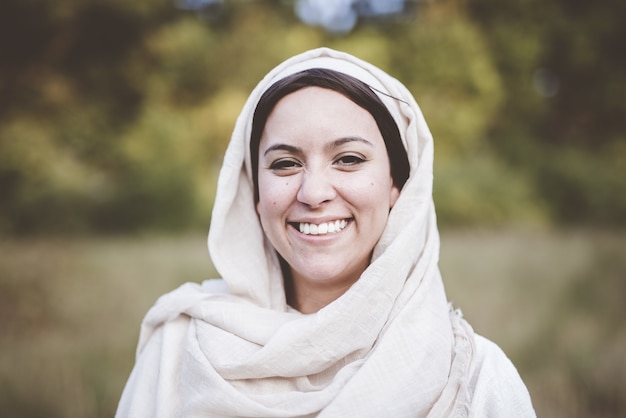 Flacher Fokusschuss einer Frau, die ein biblisches Gewand trägt und zur Kamera lächelt