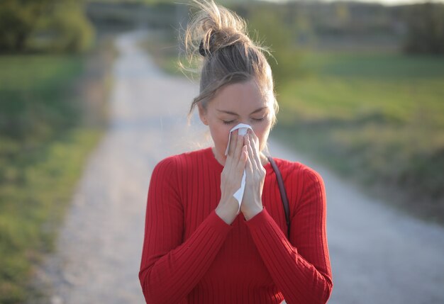 Flacher Fokusschuss einer Frau, die rote Bluse trägt, die saisonale allergische Reaktionen hat