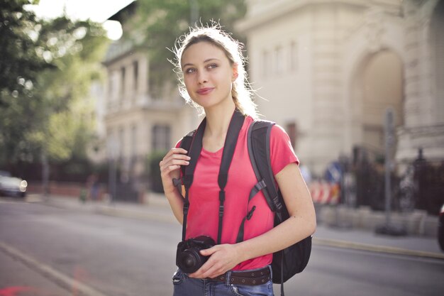 Flacher Fokusschuss einer jungen Frau, die eine Stadtrundfahrt macht und in den Händen eine Kamera hält