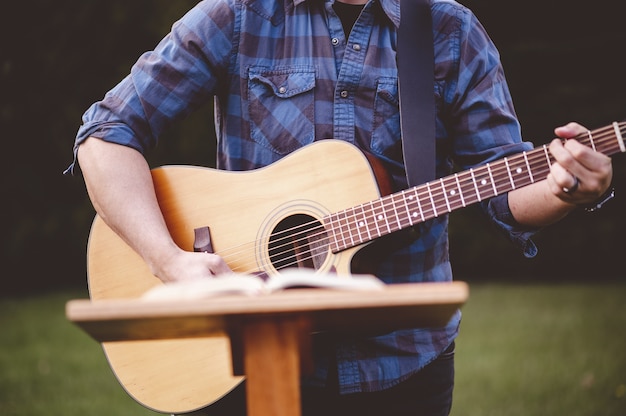 Flacher fokusschuss eines mannes, der gitarre nahe einem sprachstand spielt