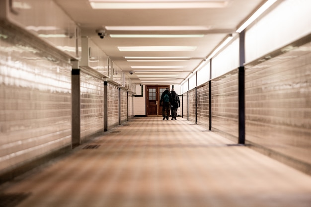 Flacher Fokusschuss von zwei Männern, die entlang eines hellen Korridors gehen