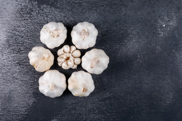 Flacher Knoblauch, der Blumenform auf dunklem Tisch bildet