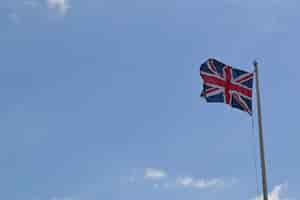 Kostenloses Foto flacher winkelschuss der flagge von großbritannien auf einer stange unter dem bewölkten himmel