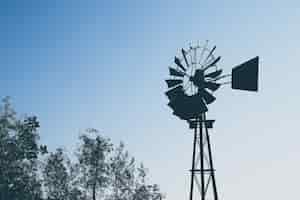 Kostenloses Foto flacher winkelschuss der silhouette einer windmühle über den bäumen