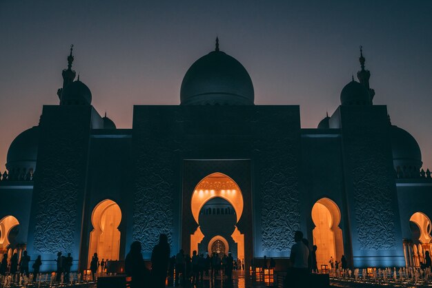 Flacher Winkelschuss einer großen Moschee in Abu Dhabi mit leuchtenden Lichtern innerhalb eines Gebäudes