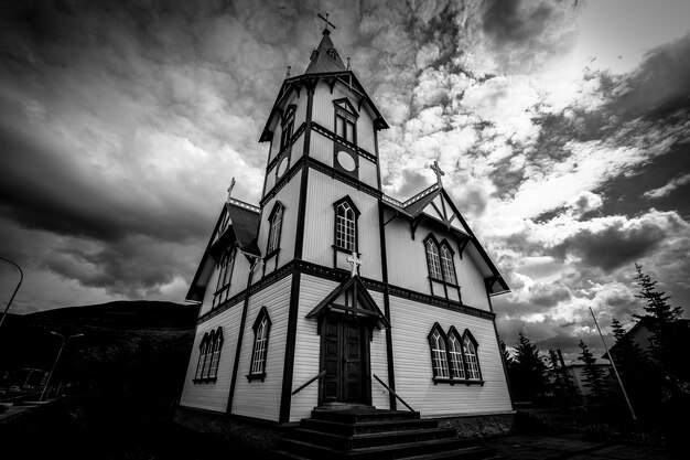 Flacher Winkelschuss einer Kirche unter einem bewölkten Himmel in Schwarzweiss