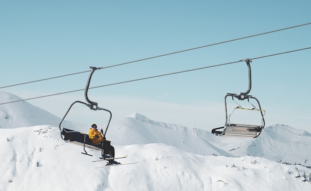 Flacher Winkelschuss einer Person, die auf einer Seilbahn in einem schneebedeckten Berg sitzt