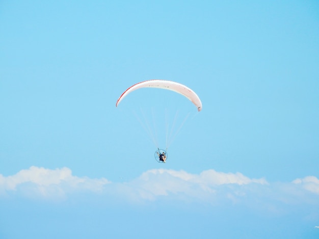 Flacher Winkelschuss einer Person, die unter dem schönen bewölkten Himmel abspringt