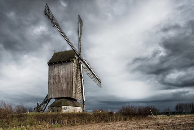 Flacher Winkelschuss einer Windmühle in einem Grasfeld unter den atemberaubenden Gewitterwolken
