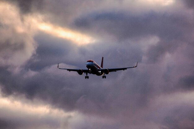 Flacher Winkelschuss eines Flugzeugs, das von einem bewölkten Himmel absteigt