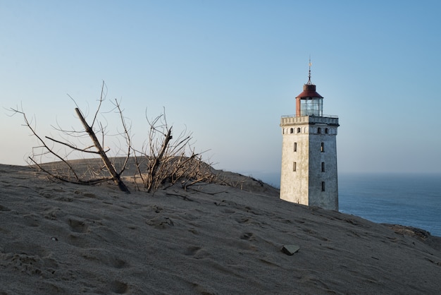 Flacher Winkelschuss eines Leuchtturms, der auf einem Hügel während des Sonnenuntergangs steht