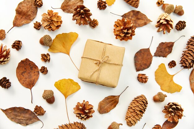 Flaches Geschenk in der Mitte eines Kranzes aus Herbstlaub und Nadelbaumkegeln
