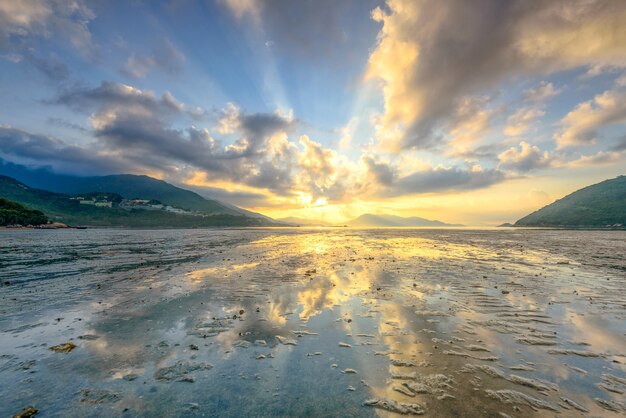 Flachwinkelaufnahme des Ozeans unter den atemberaubenden Lichtern und Wolken am blauen Himmel