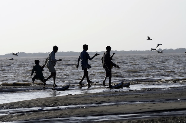 Kostenloses Foto flachwinkelaufnahme von leuten, die am strand spazieren gehen