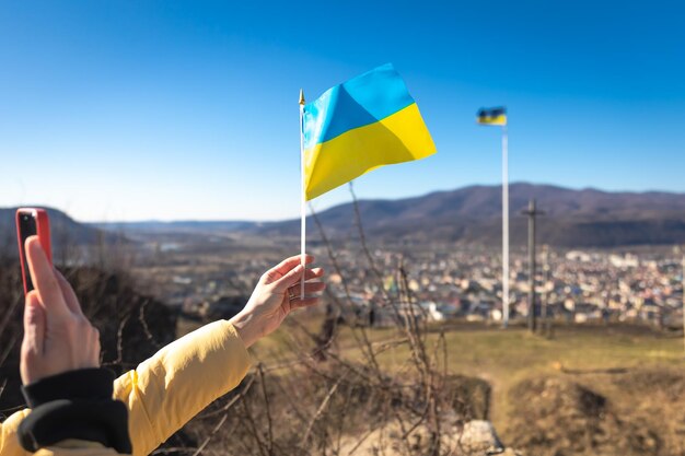 Flagge der Ukraine in weiblichen Händen gegen den Himmel