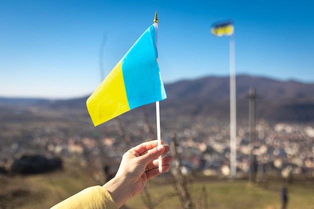 Flagge der Ukraine in weiblichen Händen gegen den Himmel