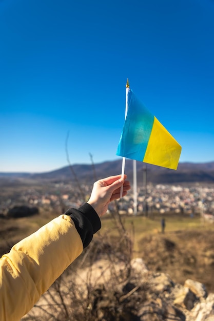 Flagge der Ukraine in weiblichen Händen gegen den Himmel