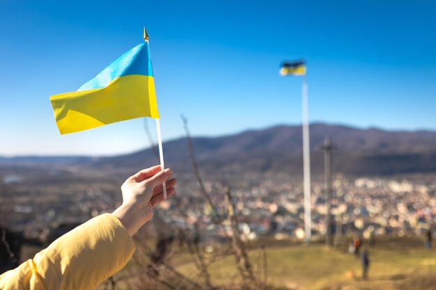 Flagge der Ukraine in weiblichen Händen gegen den Himmel