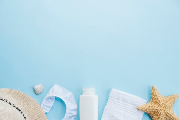 Flasche in der Nähe von Handtuch mit Seestern und Hut