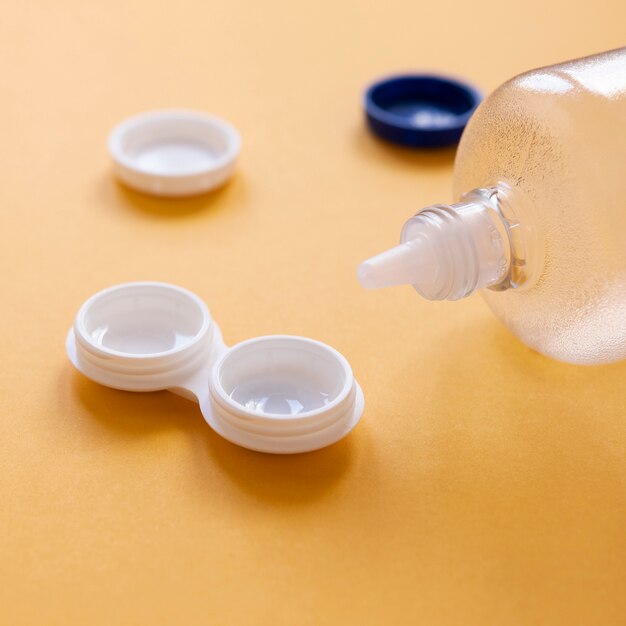 Flasche mit Objektivlösung und Objektivkasten auf orange Hintergrund