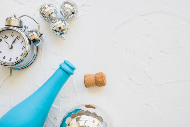 Flasche mit Uhr und Flitter auf weißer Tabelle