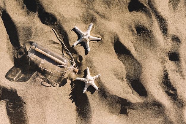 Flasche und Seesterne auf dem Sand