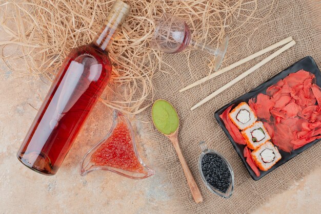 Flasche Wein mit Weinglas und Sushi auf Sackleinen