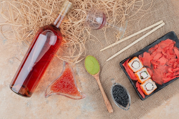 Flasche Wein mit Weinglas und Sushi auf Sackleinen