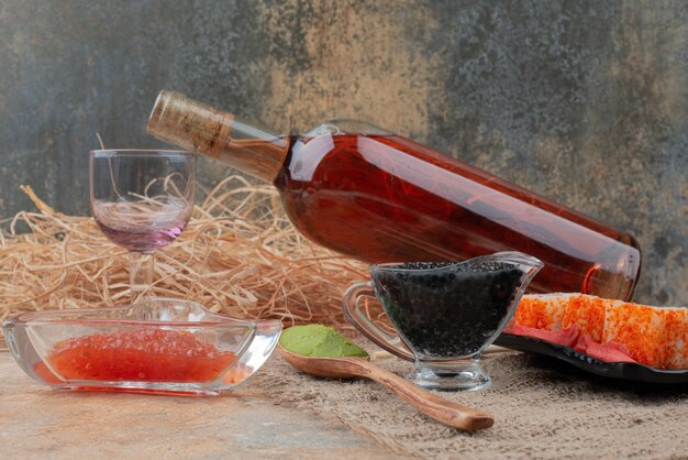 Flasche Wein mit Weinglas und Sushi auf Sackleinen