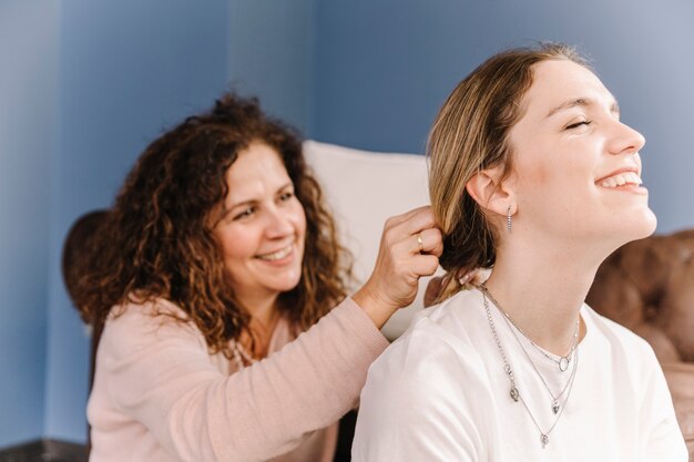 Flechtendes Haar der netten Mutter der Tochter