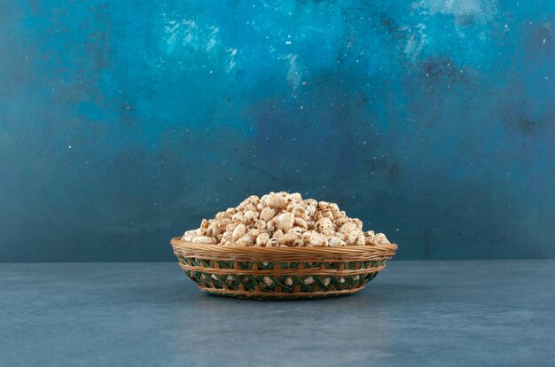 Flechtkorb gefüllt mit einer Portion knuspriger Cornflakes auf blauem Hintergrund. Foto in hoher Qualität