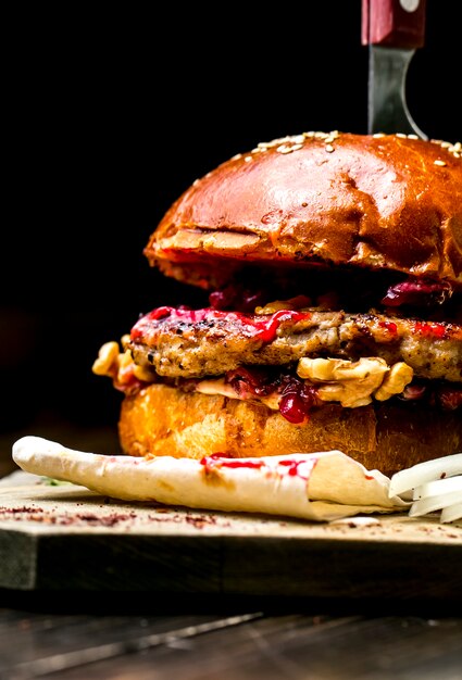 Fleisch Burger auf Holzbrett Tomaten Zwiebel Bohnen Walnüsse Seitenansicht