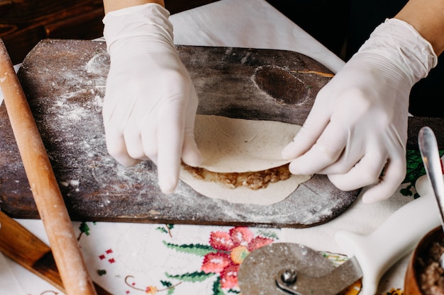 Fleisch Qutab im Prozess der Herstellung von Teig kochen auf braunem Holz rustikalen Schreibtisch