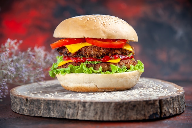 Fleischburger der vorderansicht mit käsesalat und tomaten auf dem dunklen hintergrund