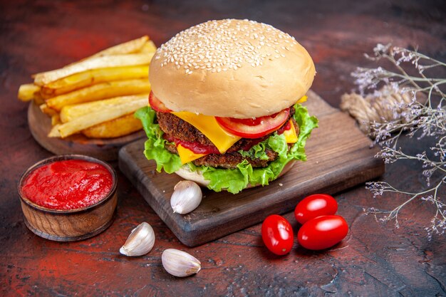 Fleischburger der Vorderansicht mit Käsesalat und Tomaten auf dem dunklen Hintergrund