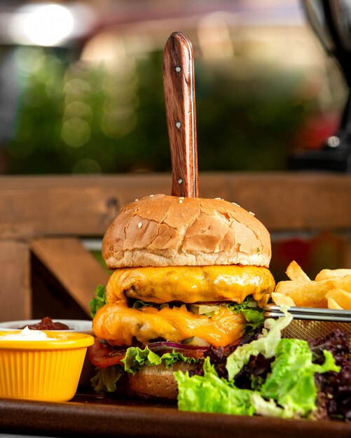 Fleischburger von der Seite mit einem festsitzenden Messer mit Pommes Frites und Suppen auf Tablett