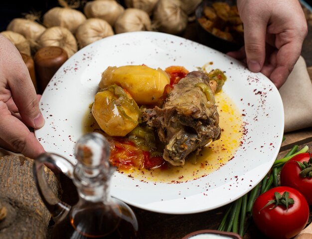 Fleischeintopf mit Kartoffeln und öliger Suppe in der weißen Platte.