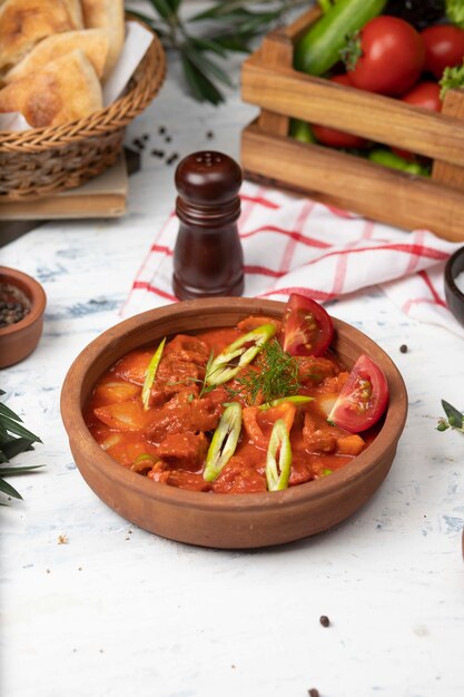 Fleischkartoffeleintopf mit Tomatensauce und Pfeffer in der Tonwarenschüssel.