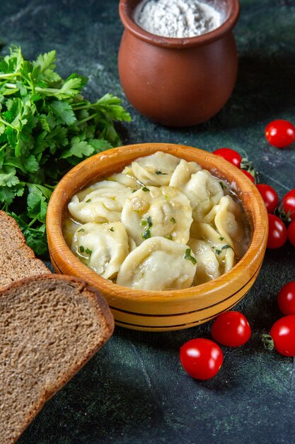 Fleischknödel von vorne mit frischen Kirschtomaten und Gemüse auf dunkler Oberfläche