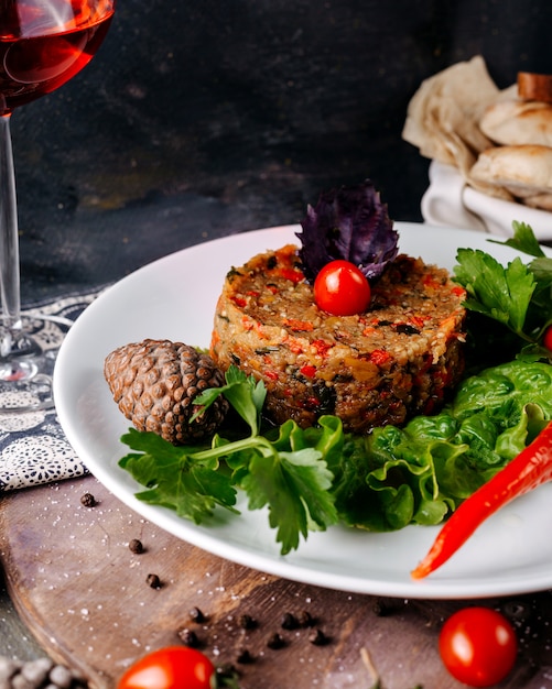 Fleischmehl zusammen mit grünem Salat und roter Kirschtomate in weißem Teller auf der grauen Oberfläche