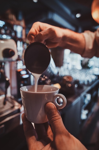 Fleißiger Barista bereitet frischen Latte für Kunden für die Kaffeepause in der Caffeteria vor.